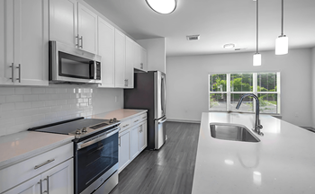 A modern kitchen with white cabinets and stainless steel appliances.